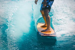 man riding wave with orange surfboard